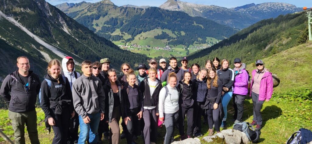 Wanderguppe in den Alpen mit Blick auf ein entferntes Tal