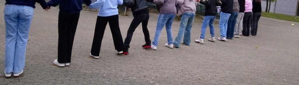 Schüler halten sich an den Händen und stehen Fuß an Fuß.