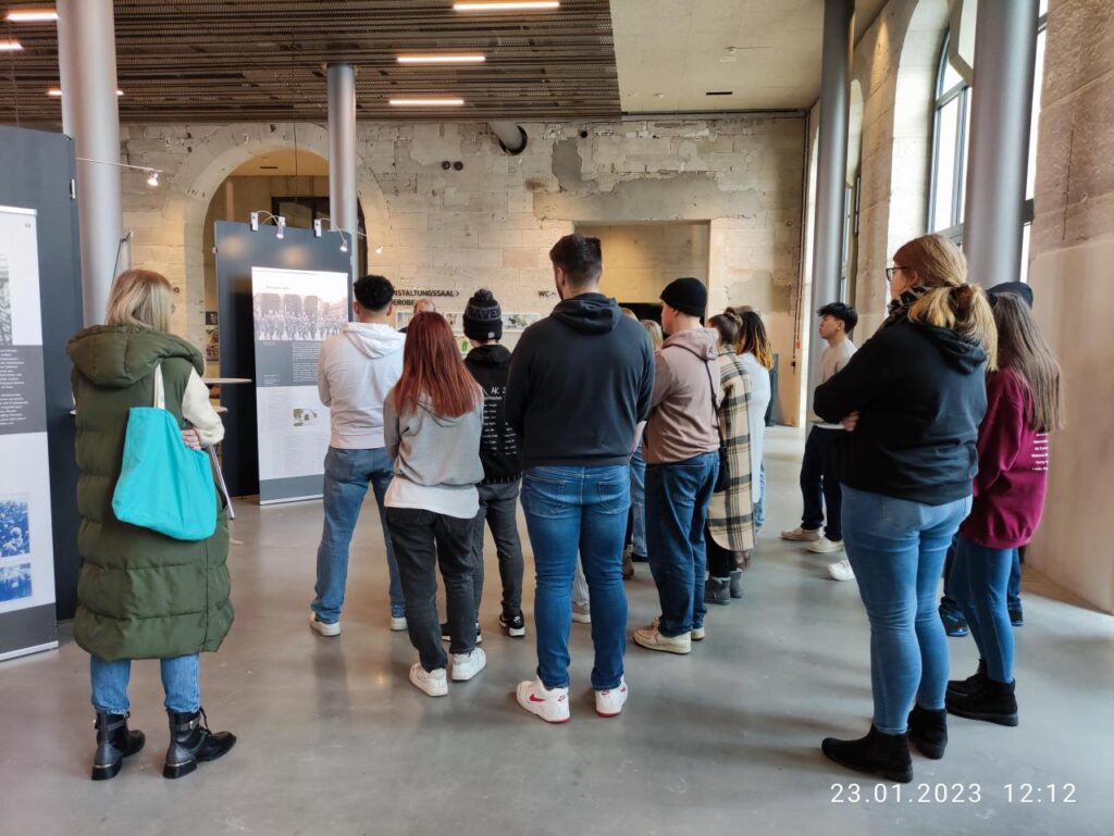 Schülergruppe hört einem Führer in der Ausstellung zu