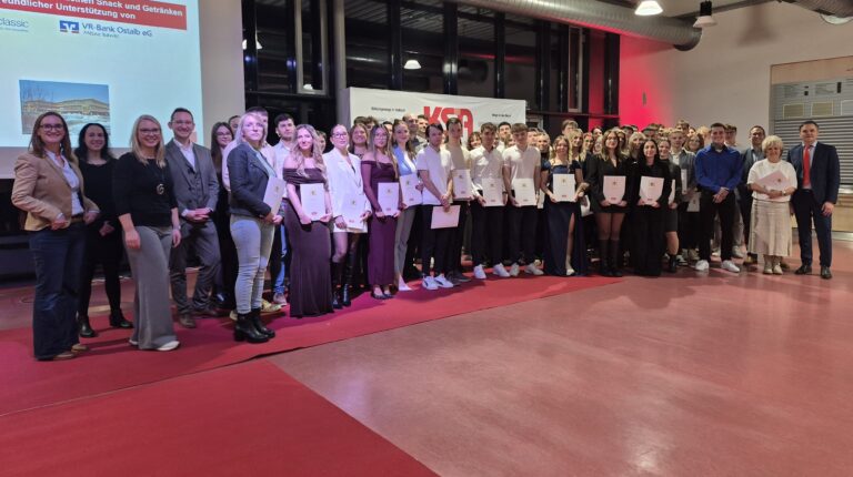 Schülerinnen und Schüler an einer Abschlussfeier mit Zeugnissen in der Hand