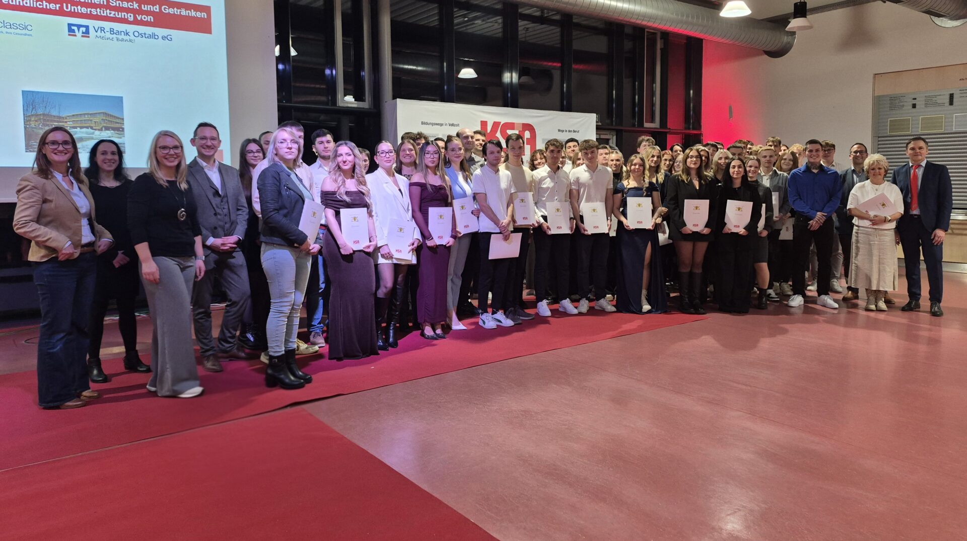 Schülerinnen und Schüler an einer Abschlussfeier mit Zeugnissen in der Hand
